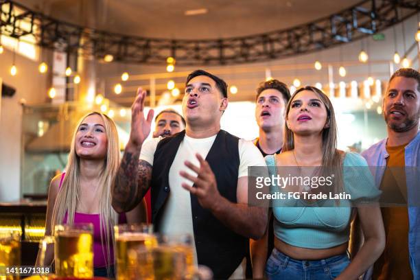 friends watching a sport match at a bar - basketball match on tv stockfoto's en -beelden