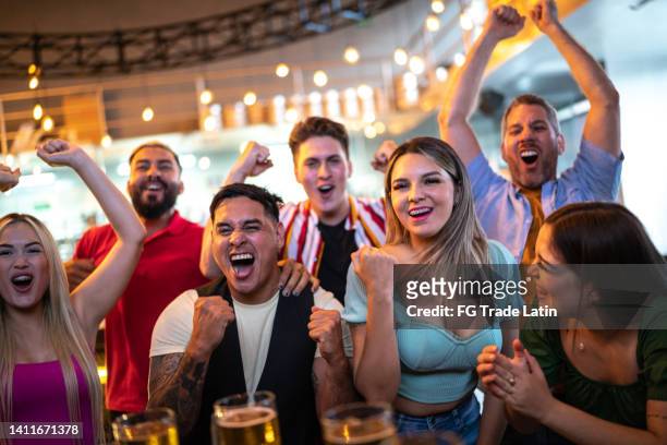 friends watching and celebrating a sport match at a bar - social tv awards stockfoto's en -beelden