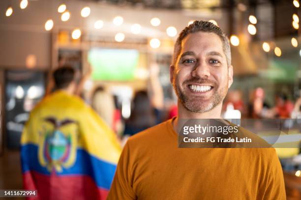 portrait of a mid adult men watching sports with friends at bar - latin american flags stock pictures, royalty-free photos & images
