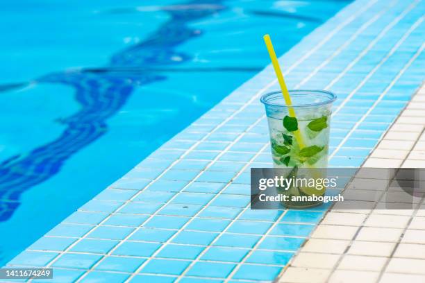 plastic cup with lime and mint water next to a swimming pool - drinkwater kante stock-fotos und bilder