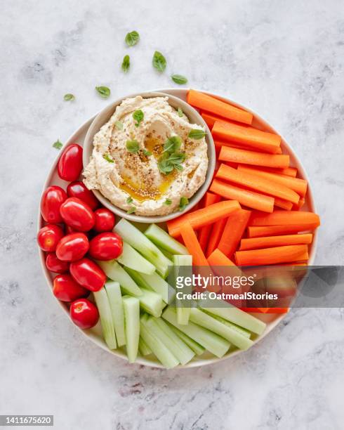 overhead view of a bowl of hummus with cherry tomatoes, carrot and cucumber batons - dip stock-fotos und bilder