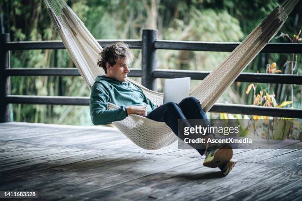 giovane uomo d'affari creativo lavora dall'amaca all'aperto - hammock foto e immagini stock
