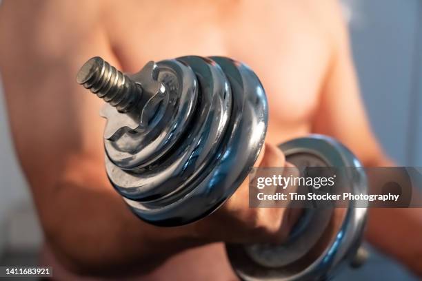 a man exercising using metal dumbbells - lifting heavy objects stock pictures, royalty-free photos & images