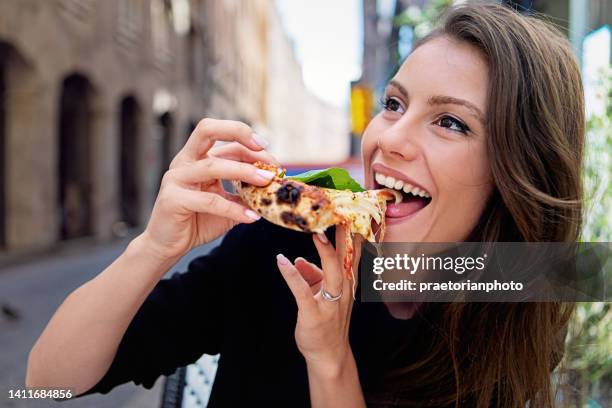 porträt einer jungen frau, die in einem restaurant pizza isst - woman eating pizza stock-fotos und bilder