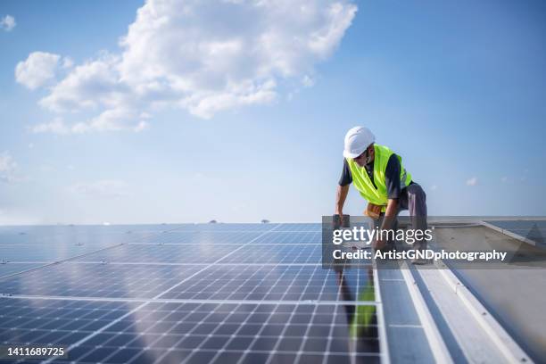 man on roof installing solar panel system. - zonnepanelen stockfoto's en -beelden