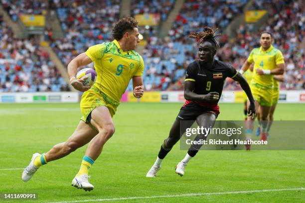 Mark Nawaqanitawase of Team Australia runs with the ball whilst under pressure from Aaron Ofoyrwoth of Team Uganda during the Men's Rugby Sevens...
