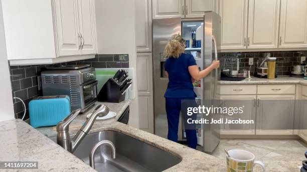 nurse in scrubs getting her lunch - multitasking nurse stock pictures, royalty-free photos & images