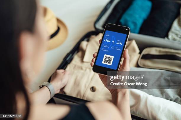 young woman booking flight online with smart phone, getting ready to go travelling - airplane tickets stock pictures, royalty-free photos & images