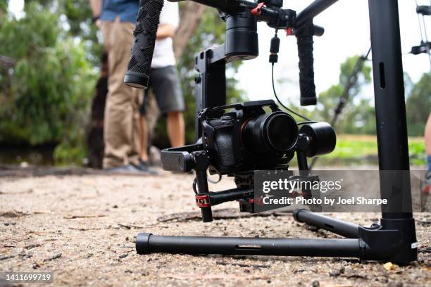 a mirrorless camera on a gimbal with people in the background - film documentaire photos et images de collection
