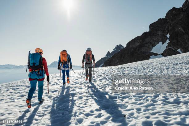 three people walk away down a high mountain glacier - canada landscape room for type stock-fotos und bilder