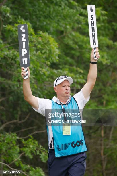 Paddle signs reading "SHHHH" and "ZIP IT" are displayed by a marshal during day one of the LIV Golf Invitational - Bedminster at Trump National Golf...