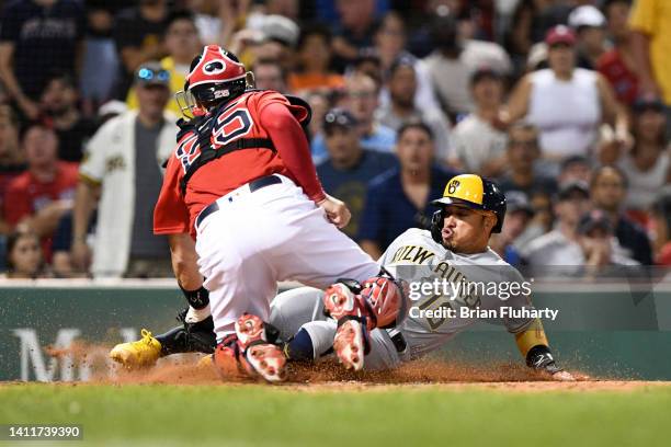 Kolten Wong of the Milwaukee Brewers slides safely into home to score a run as Kevin Plawecki of the Boston Red Sox attempts to make a tag during the...