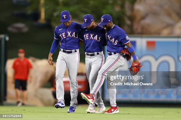 Elier Hernandez, Leody Taveras and Adolis Garcia of the Texas Rangers celebrate after defeating the Los Angeles Angels during the ninth inning at...