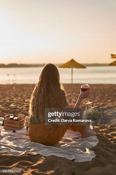 a beautiful woman at the back on the sandy shore. - picnic rug stockfoto's en -beelden