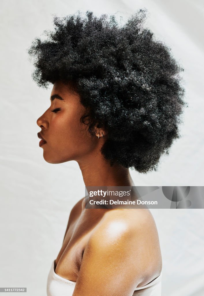 Profil latéral d’une femme africaine avec un afro isolé sur fond blanc en studio. Belle femme aux cheveux bouclés montrant une peau parfaite pour les cosmétiques, et une beauté naturelle pour les produits de maquillage