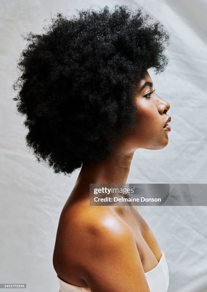 Profilo laterale di donna africana con afro isolato su uno sfondo bianco in uno studio. Bella femmina con capelli ricci che mostrano una pelle perfetta per i cosmetici e bellezza naturale per i prodotti per il trucco
