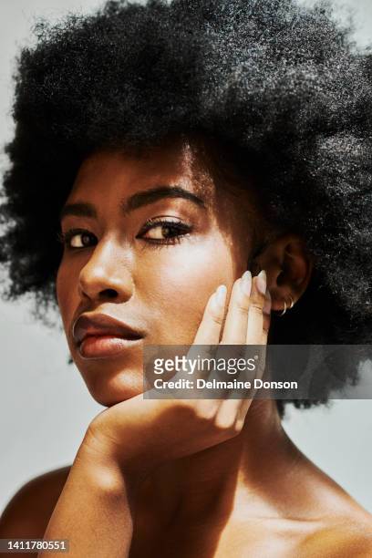 beautiful black woman with an afro and flawless clear and clean skin. portrait of a gorgeous african female beauty model face after a skincare routine with the sun shining on her - black makeup stockfoto's en -beelden