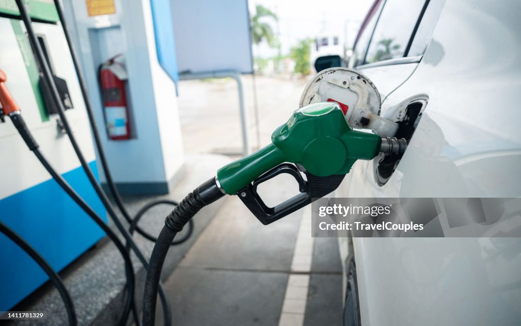 Transport and industry concept. Refilling the car. A refueling valve is inserted into the fuel filler neck. White car at gas station being filled with fuel