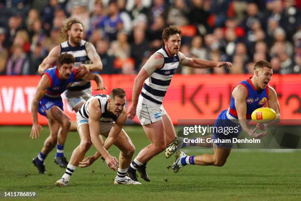 Robbie McComb of the Bulldogs handballs during the round 20 AFL match between the Geelong Cats and the Western Bulldogs at GMHBA Stadium on July 30,...