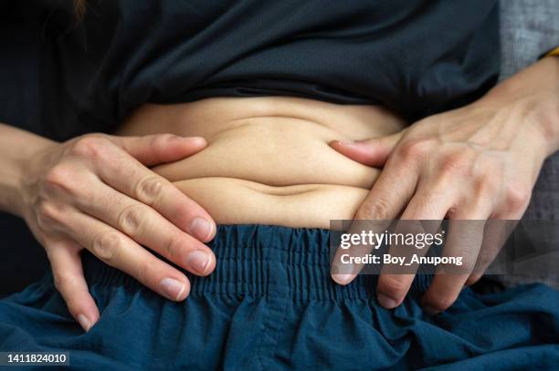 close up of unidentified person touching fat belly. - menschlicher bauch stock-fotos und bilder