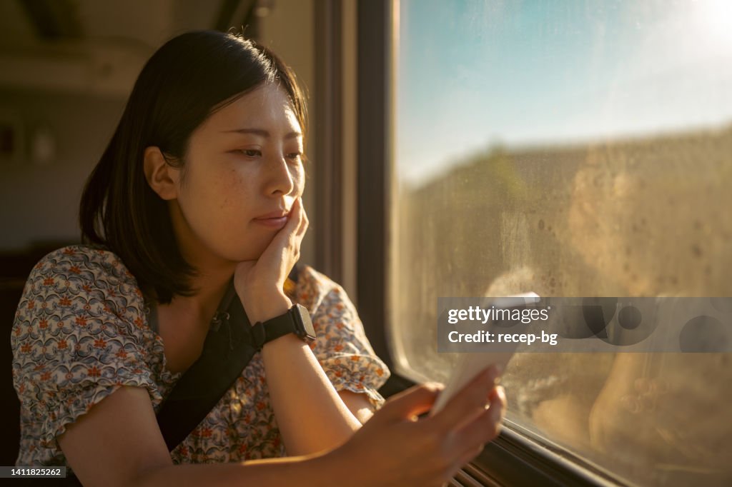 Young female tourist using her mobile phone in train