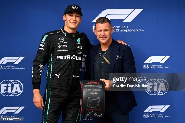 Pole position qualifier George Russell of Great Britain and Mercedes is presented with the Pirelli Pole Position trophy by Tom Kristensen during...