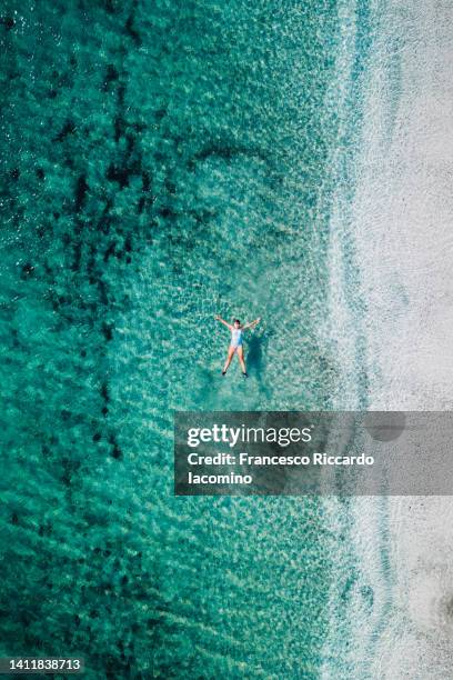 woman bathing in la pelosa amazing beach in stintino, sardinia island, italy. aerial view - iacomino italy stock-fotos und bilder