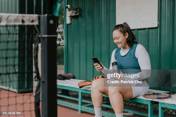 asian chinese female tennis player resting at bench while using handphone - tennis outfit stock pictures, royalty-free photos & images
