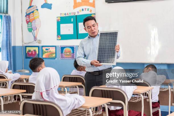 asian teacher showing solar panel to students - mid adult ストックフォトと画像