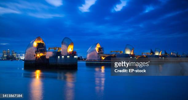 section of the river thames flood barrier at dusk with canary wharf and o2 arena in the background, london, england, united kingdom, europe - the o2 england stock pictures, royalty-free photos & images