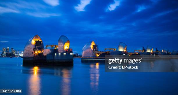 section of the river thames flood barrier at dusk with canary wharf and o2 arena in the background, london, england, united kingdom, europe - the o2 england 個照片及圖片檔