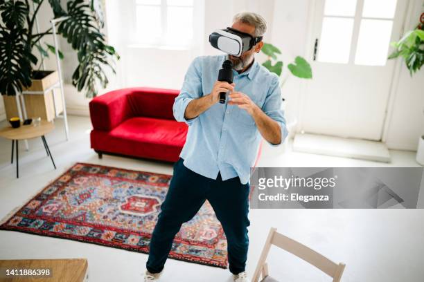 mature man wearing glasses of virtual reality singing at karaoke while listening his favorite music at home - concert icon stock pictures, royalty-free photos & images