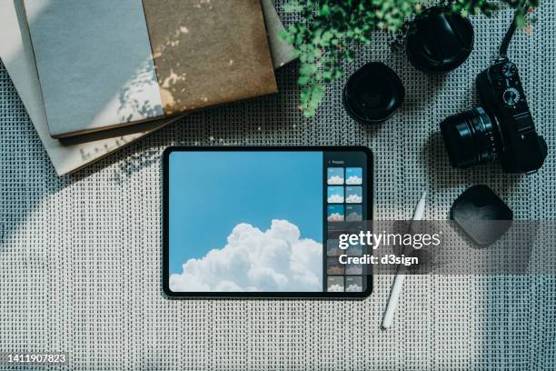 directly above shot of digital tablet, camera, lens and books on black and white background against sunlight. designer / photographer's collection on workstation - office work flat lay foto e immagini stock