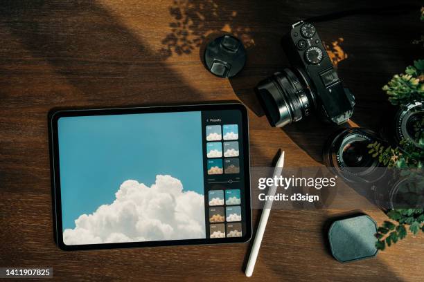 directly above shot of digital tablet, camera and lens on rustic wooden desk against sunlight. designer / photographer's collection on workstation - flatlay stock-fotos und bilder