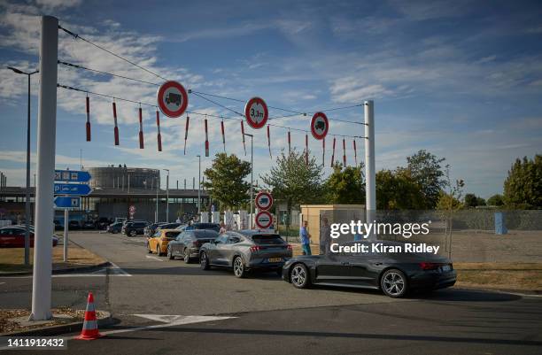 Motorists queue for an electric charging point at a service station on the A16 Motorway as holiday makers take to the roads in what is often called...