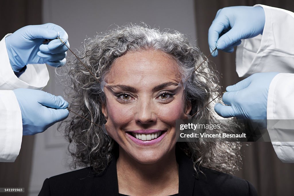 A senior woman has face pulled by surgeons