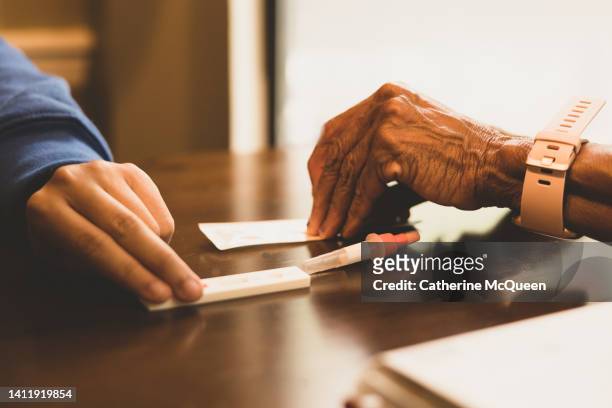 mixed-race granddaughter assists black grandmother with at-home covid-19 test - prophylaxie stock pictures, royalty-free photos & images