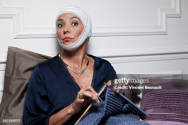 senior woman with bandages on head knitting - bandage stockfoto's en -beelden