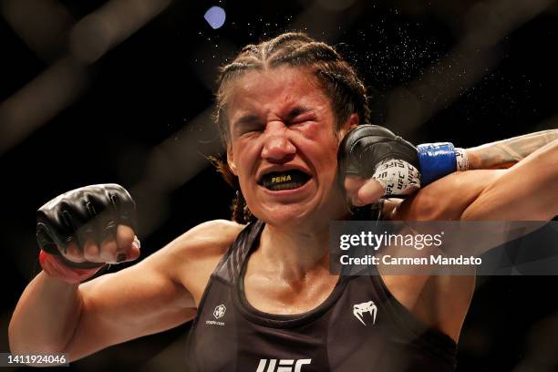 Julianna Pena takes a punch from Amanda Nunes of Brazil in their bantamweight title bout during UFC 277 at American Airlines Center on July 30, 2022...