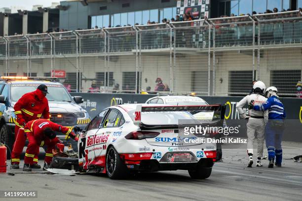 Andre Heimgartner driver of the Brad Jones Racing Holden Commodore ZB is attended to by medical staff after colliding with Thomas Randle driver of...