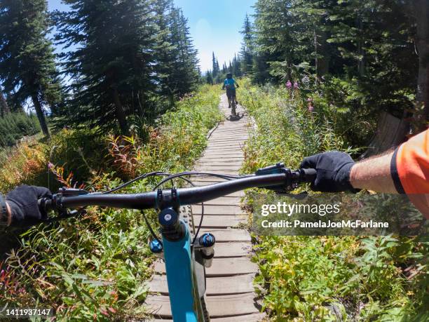 pov, senior multiracial couple mountain biking on alpine boardwalk trail - extreme sports point of view stock pictures, royalty-free photos & images