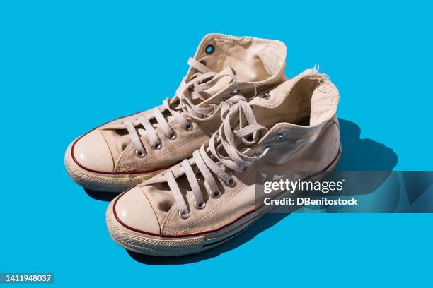 old style worn white basketball shoe on blue background. fashion, modern, retro and casual footwear concept. - blue shoe foto e immagini stock