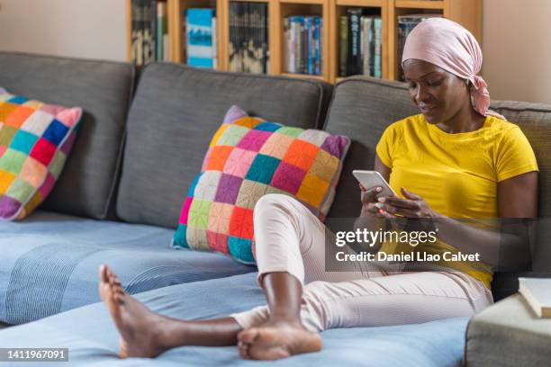 woman with cancer after radiation therapy at home reading text messages - cellphone cancer illness stock pictures, royalty-free photos & images