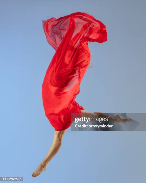tänzersprung auf blauem hintergrund mit rotem stoff - modern dance stock-fotos und bilder