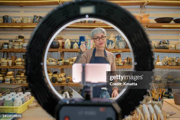 senior artist woman vlogger making social media video about pottery sale for the internet. - kunsthandwerk stock-fotos und bilder