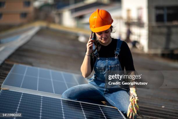 los trabajadores colocan paneles solares en el techo de un edificio. - panel fotografías e imágenes de stock