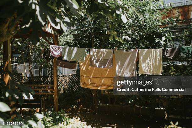 damp clothing hanging on a washing line - hanging in garden photos et images de collection