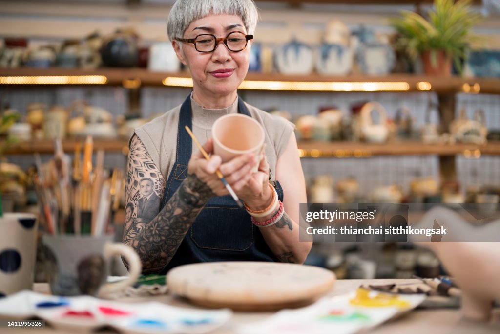 Creating pottery painting a cup in her small crafts workshop.