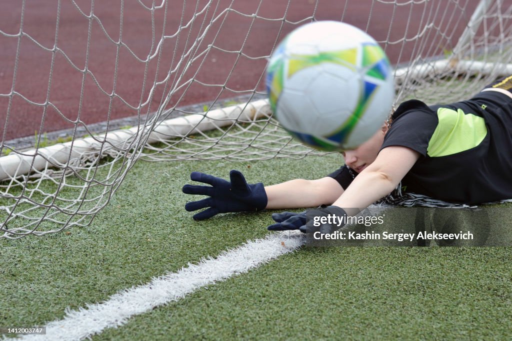 Female goalkeeper catching a soccer ball.