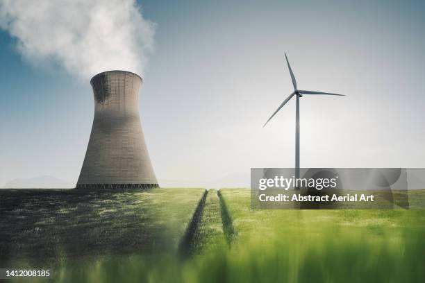 low angle shot showing a power station and a wind turbine side by side in an agricultural field, united kingdom - centrale elettrica foto e immagini stock